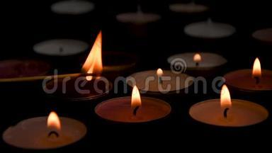 在黑色背景下，点燃的茶光蜡烛的特写组合在一起。 浪漫气氛